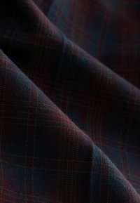 Rutig tyg i mörkröda och marinblå nyanser, med en texturerad yta som känns mjuk. Mönstret visar en klassisk rutig design.