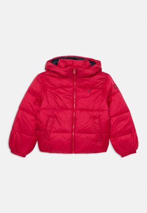 Chaqueta de abrigo roja con capucha, cierre de cremallera y puños elásticos. Presenta dos bolsillos frontales y un detalle de logo en el pecho. Textura suave y acolchada.