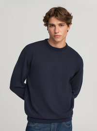 Maglione blu navy lavorato a maglia con scollo rotondo, polsini e orlo a coste. Il tessuto sembra liscio con una texture sottile. Adatto per un abbigliamento casual.
