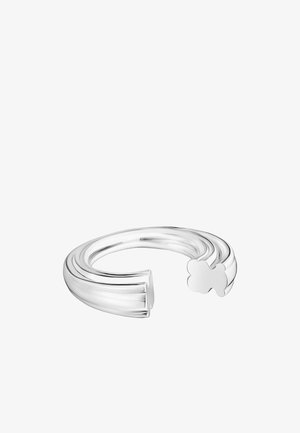 Bague en argent fin avec un design ondulé, présentant une texture lisse et un accent décoratif en forme de trèfle à l'extrémité ouverte.