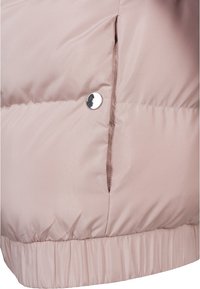 Närbild av en ljusrosa vadderad jacka med en silverfärgad tryckknapp och elastisk fåll, som visar quiltade sömmar och ficköppning.