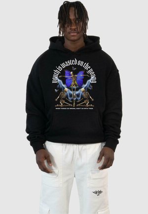 Svart hettegenser med livlig grafikk av skjeletter og en blå sommerfugl, med tekst. Myk stoff, pullover-stil og løs passform.