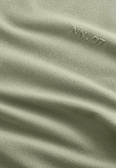 Ljusgrön tyg med en slät textur, med präglad "NN. 07" detalj, som visar subtila veck och en enhetlig utseende.