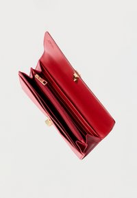 Portofel roșu din piele deschis, cu mai multe sloturi pentru carduri, un buzunar central cu fermoar pentru monede și clemă aurie pe fundal alb.
