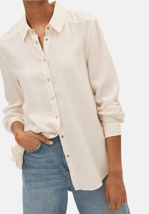 Kremfarvet skjorte med knapper, krave, lange ærmer og en diskret glans, kombineret med lyseblå denimjeans. Casual pasform med en afslappet silhuet.