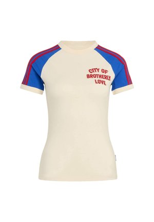 T-shirt court crème à manches courtes avec manches raglan bleues, rayures rouges sur les épaules et texte rouge « City of Brotherly Love » sur la poitrine.