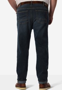 Jeans in denim blu scuro con taglio dritto, dotati di due tasche posteriori e un accentuato cinturino in pelle marrone. Il tessuto ha una texture liscia.