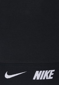 Top atletico nero realizzato in tessuto morbido, con una texture liscia. Logo Nike bianco ben visibile. Design semplice senza motivi.