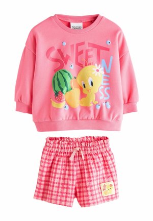 Rosa Langarm-Sweatshirt mit Tweety-Vogel, Früchten und dem Schriftzug "SÜSSE", kombiniert mit rosa karierten Shorts mit elastischem Bund und einem Tweety-Aufnäher.
