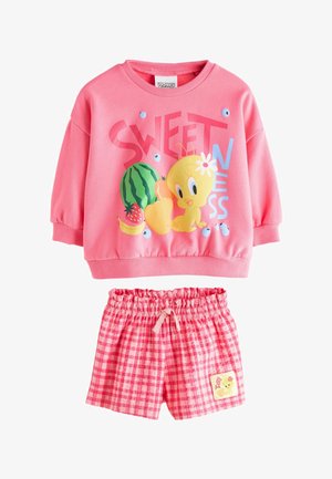 Felpa rosa a maniche lunghe con l'uccellino Tweety, frutti e la scritta "SWEETNESS", abbinata a pantaloncini rosa a quadretti con vita elasticizzata e una toppa di Tweety.