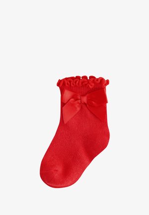 Calza rossa lavorata a maglia con un bordo arricciato e un nastro in raso decorativo sul lato. La trama del tessuto è liscia ed elastica, progettata per una vestibilità aderente.