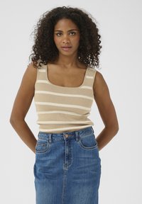 Top en rib d beige avec des rayures horizontales blanches, décolleté carrée et bretelles larges, associé à une jupe en denim bleu taille haute.