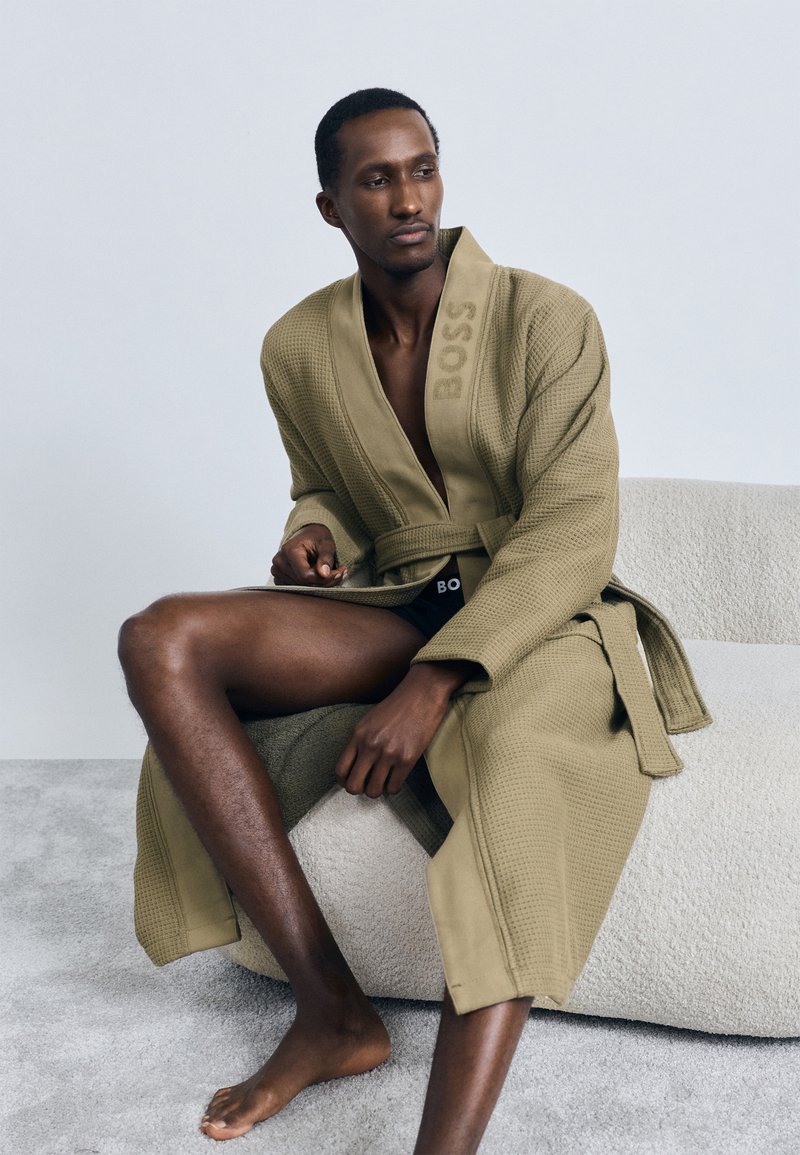 Accappatoio verde oliva con trama a nido d'ape e cintura, con il nome del marchio "BOSS" in rilievo sul colletto. Senza cappuccio.