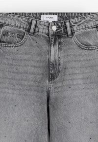 Šedé denimové džíny se zesvětlením, s tradičním pasem, předními kapsami a rozptýlenými malými ozdobami.