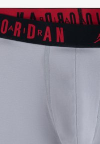 Szürke pamut boxer alsónadrág fekete és piros elasztikus derékrésszel, amelyen a "AIR JORDAN" felirat nagy, nagybetűs formában szerepel.