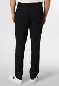 Pantalones negros de tejido suave, con corte recto, dos bolsillos traseros y combinados con zapatillas blancas.