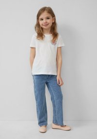 Witte katoenen t-shirt met een watermeloenafbeelding, gecombineerd met lichtblauwe spijkerbroek en lichtbeige platte schoenen. Eenvoudig design, casual fit.