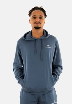 Sweat-shirt à capuche bleu foncé, avec une texture lisse et une poche kangourou sur le devant. Logo sur la poitrine, avec des cordons de serrage et un ourlet côtelé.