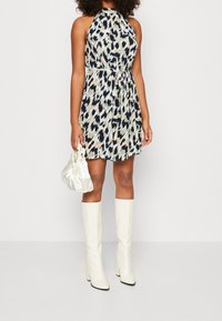 Šaty s halter výstřihem a barevným abstraktním vzorem v modré, růžové a krémové barvě. Dodány s bílými vysokými kozačkami a krémovou kabelkou.