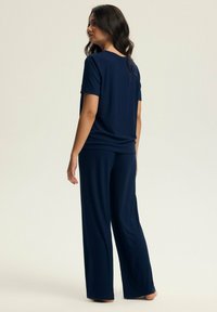 Granatowy zestaw odzieży domowej o prążkowanej teksturze; top z krótkim rękawem i spodnie z szerokimi nogawkami. Miękka tkanina, charakteryzująca się luźnym krojem.