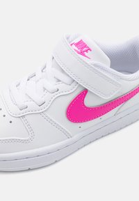 Hvide lædersneakers med en pink swoosh, mesh-tunge, snørebåndslukning og velcro-rem. Har perforeret tå for åndbarhed.