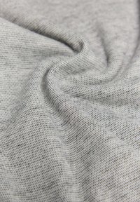 Tejido gris texturizado con un patrón de malla fina, que muestra una caída suave y una apariencia blanda, ideal para prendas y accesorios.