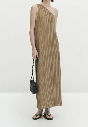 Ärmelloses, langes, beigefarbenes, plissiertes Kleid mit einem Schulterriemen, kombiniert mit schwarzen Sandalen und einer kleinen schwarzen Handtasche.