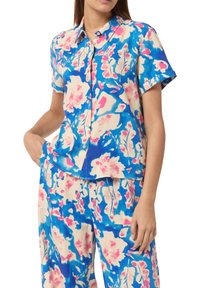 Camicetta a maniche corte in tessuto leggero con un motivo floreale blu e rosa, caratterizzata da una chiusura a bottoni e una vestibilità comoda.