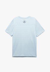 Camiseta de manga corta azul claro con un pequeño logo de un velero azul oscuro y texto circular cerca de la parte superior de la nuca.