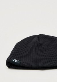 Μαύρο ριγέ σκουφάκι φτιαγμένο από πλεκτό ύφασμα, με διπλωμένη περιφέρεια και μια μικρή ετικέτα λογότυπου σε αντίθεση χρώματος.