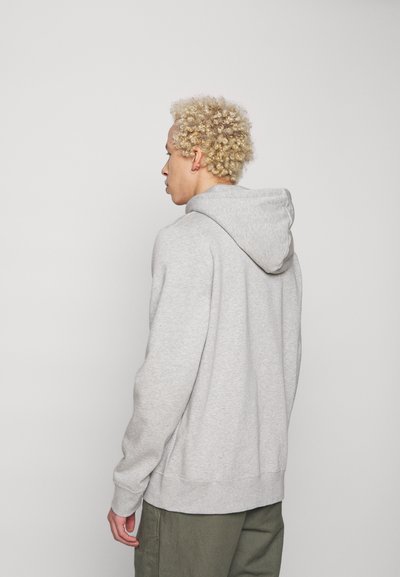 Grå bomulds hoodie med snøre i hætten, ribbede manchetter og kant. Blød tekstur, afslappet pasform og ensartet design uden yderligere mønstre eller detaljer.