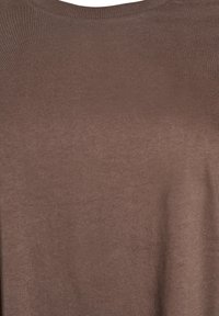 Brun stickad tröja med rund halsringning och slät textur. Tyget verkar mjukt och något glänsande, med en enhetlig färg.