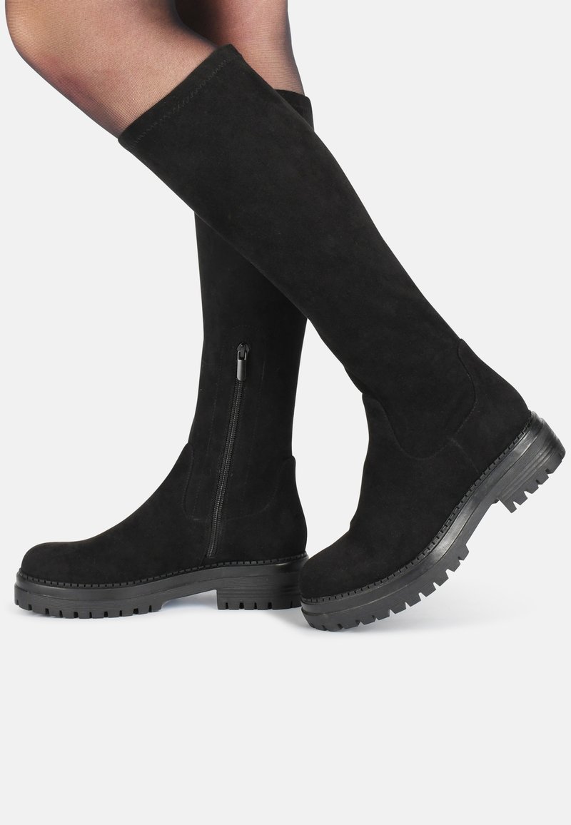 Botas de ante negras hasta la rodilla con punta redondeada y suela de goma gruesa; presentan un cierre lateral con cremallera y un acabado suave y texturizado.