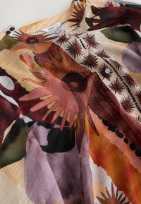Farverig bluse i let materiale med abstrakte blomsterprint, rund halsudskæring og knapdetaljer foran.