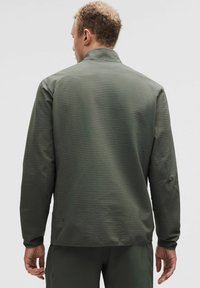 Mørkegrøn jakke med et tekstureret mønster, høj krave og lange ærmer. Designet omfatter subtile detaljer og en afslappet pasform.