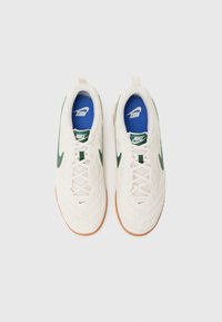 Hvite sporty joggesko med grønne detaljer, teksturert overdel, perforerte elementer og blå innersåler. Gummisåle for godt grep.