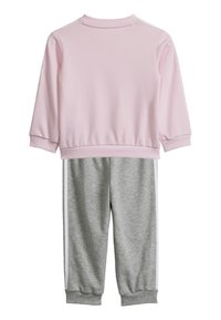 Felpa rosa con collo a costine e maniche lunghe, abbinata a pantaloni della tuta grigi con strisce bianche sui lati e polsini elastici.