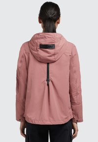 Jachetă cu glugă roz deschis, cu fermoar, manșete elastice și un patch pe spate cu marcă. Textură netedă, design casual, potrivire ușor lejeră.