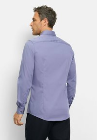 Tailliertes, langärmliges Hemd aus helllila Stoff mit glatter Textur, Knopfmanschetten und einem klassischen Kragen. Maßgeschneiderter Rückendesign.