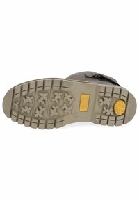 Brązowa podeszwa na buty outdoorowe z głębokimi rowkami do przyczepności, żółtym akcentem oraz metką z nazwą marki. Teksturowana guma zapewniająca przyczepność i trwałość.