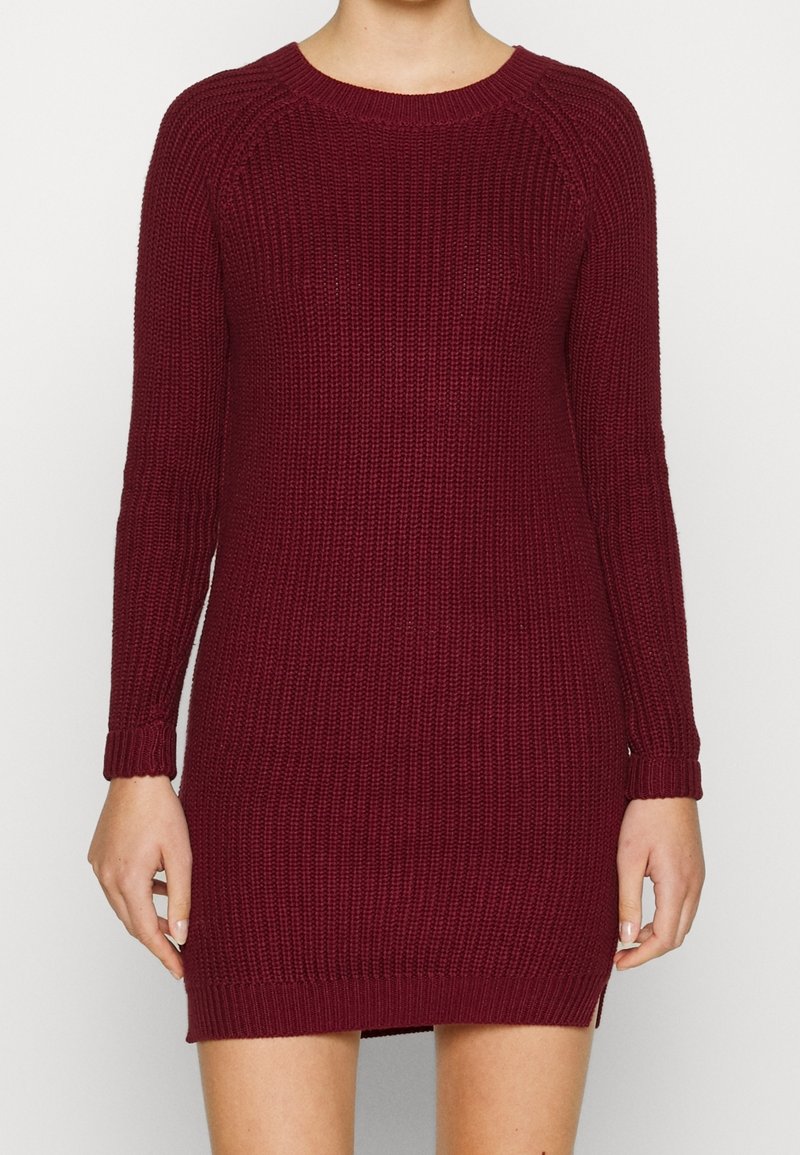 Abito in maglia color bordeaux con maniche lunghe, scollo a giro, texture a costine e spacchi laterali, che offre una silhouette aderente.