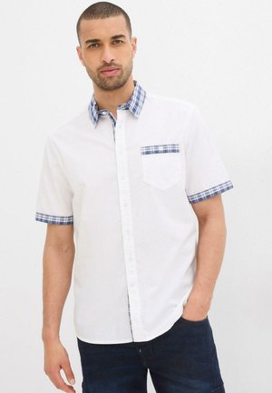 Camicia bianca a maniche corte con colletto e polsini a quadri blu e bianchi. Presenta una piccola tasca sul petto, chiusura con bottoni e tessuto in cotone.