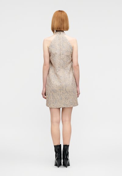 Φόρεμα με λαιμόκοψη halter σε υφή μπεζ ύφασμα με λεπτά μοτίβα, εφαρμοστό μπούστο και ίσια φούστα. Συνδυάζεται με μαύρες μυτερές μποτάκια στους αστραγάλους.