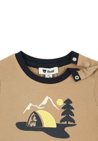 Camiseta de algodón color beige con cuello acanalado negro y cierre de botones a presión, adornada con una escena de camping en bordado amarillo, negro y blanco.