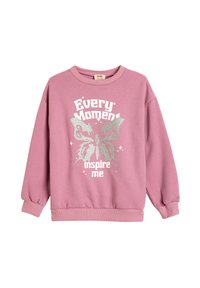 Sudadera rosa de manga larga, con un gráfico de mariposa plateada y el texto "Cada momento me inspira" en la parte frontal. Textura suave.