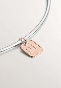 Collar de metal plateado con un charm rectangular de oro rosa que presenta un diseño en relieve sobre una superficie lisa.