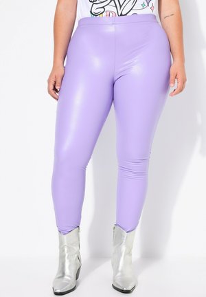Leggings morados de alto brillo con un diseño ajustado y una textura suave, combinados con botas de tobillo plateadas brillantes.