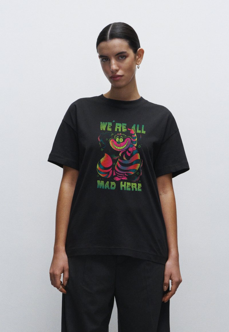 Zwarte katoenen t-shirt met kleurrijk grafisch ontwerp met de tekst "WE ZIJN ALLEMAAL GEK HIER" en speelse karakterillustraties.