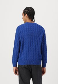 Blue knitted sweater with a textured cable pattern. Features a crew neckline, ribbed cuffs, and hem. Casual fit and solid color.