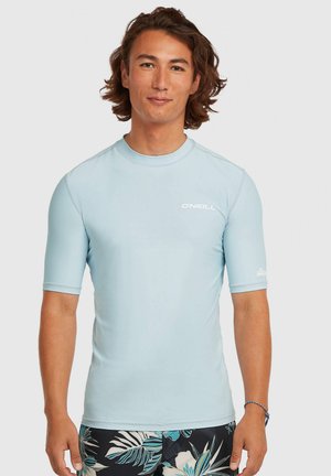 Svetlomodrý ochranný rash guard s krátkym rukávom a okrúhlym výstrihom, s bielym logom O'Neill na ľavej strane hrudi. Hladká, elastická látka. Čierne kraťasy s kvetinovým vzorom.